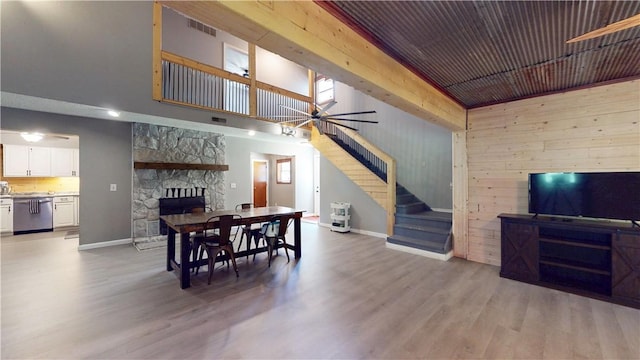 104 NE Deer Ridge Rd, Gravette, AR 72736 - dining room featuring ceiling fan, stairway, light wood-type flooring, baseboards, and wooden walls