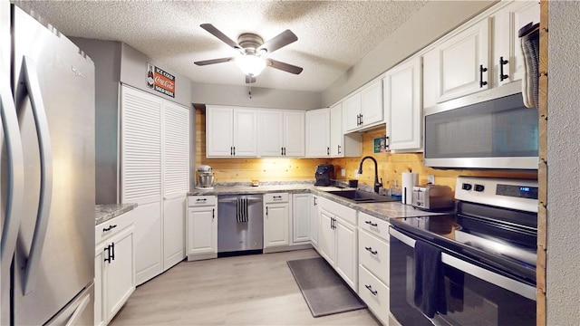 104 NE Deer Ridge Rd, Gravette, AR 72736 - kitchen featuring stainless steel appliances, a sink, ceiling fan, light wood finished floors, and white cabinetry