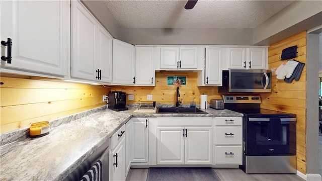 104 NE Deer Ridge Rd, Gravette, AR 72736 - kitchen with appliances with stainless steel finishes, a sink, white cabinetry, a textured ceiling, and wood finished floors