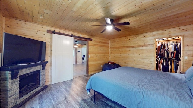 104 NE Deer Ridge Rd, Gravette, AR 72736 - bedroom with wooden walls, wood finished floors, wood ceiling, a barn door, and a fireplace