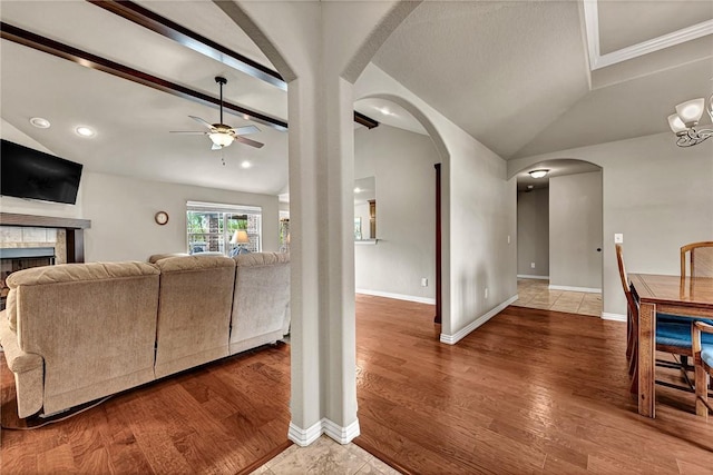 1805 SW Birch St, Bentonville, AR 72713 - living room with lofted ceiling, ceiling fan, a tile fireplace, baseboards, and arched walkways