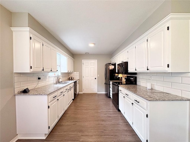 4408 W Apache Trl, Fayetteville, AR 72704 - kitchen with black appliances, a sink, white cabinetry, wood finished floors, and baseboards