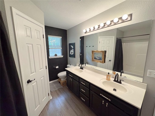 4408 W Apache Trl, Fayetteville, AR 72704 - bathroom featuring toilet, wood finished floors, a textured ceiling, a shower with shower curtain, and double vanity