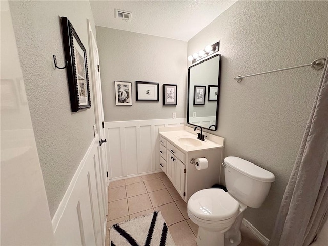 4408 W Apache Trl, Fayetteville, AR 72704 - bathroom with toilet, tile patterned floors, vanity, a textured wall, and a wainscoted wall