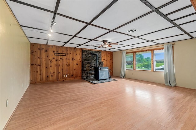 12549 Little Elm Rd, Farmington, AR 72730 - unfurnished living room with a wood stove, wooden walls, and light wood-type flooring