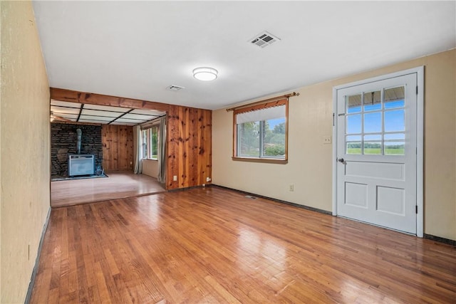 12549 Little Elm Rd, Farmington, AR 72730 - unfurnished living room featuring light wood finished floors, a wood stove, baseboards, and wooden walls