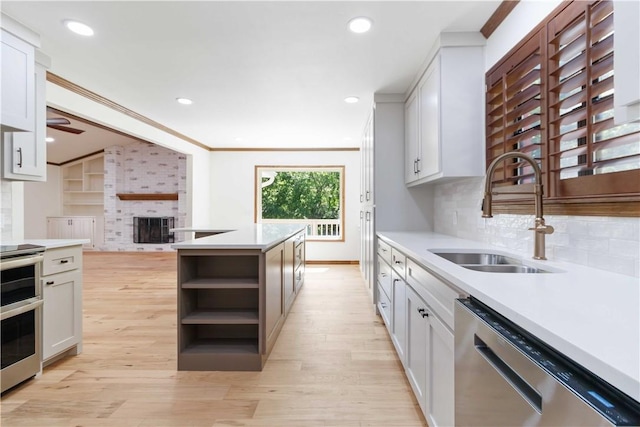 1640 N Boston Pl, Fayetteville, AR 72703 - kitchen featuring appliances with stainless steel finishes, a sink, open shelves, light wood finished floors, and a fireplace