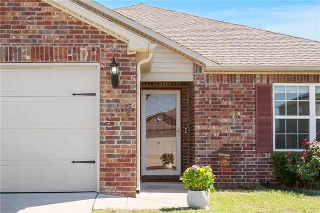 2405 Maplewood Ave, Lowell, AR 72745 - view of exterior entry with brick siding, a garage, and a shingled roof