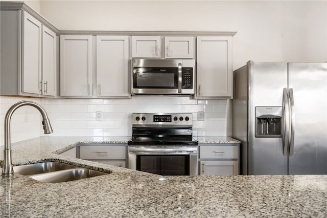 2405 Maplewood Ave, Lowell, AR 72745 - kitchen with appliances with stainless steel finishes, a sink, gray cabinets, light stone counters, and decorative backsplash