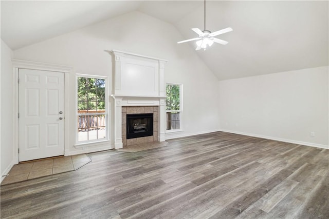 603 Highland Ct, Siloam Springs, AR 72761 - unfurnished living room featuring a tiled fireplace, wood finished floors, a ceiling fan, high vaulted ceiling, and baseboards