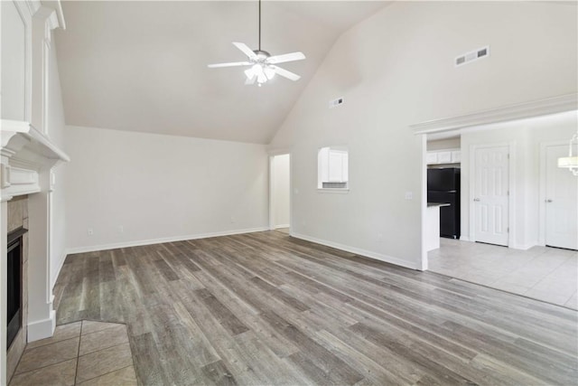 603 Highland Ct, Siloam Springs, AR 72761 - unfurnished living room featuring high vaulted ceiling, a ceiling fan, a tiled fireplace, light wood-type flooring, and baseboards