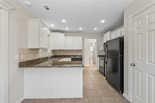603 Highland Ct, Siloam Springs, AR 72761 - kitchen featuring freestanding refrigerator, a peninsula, dark stone counters, decorative backsplash, and white cabinets