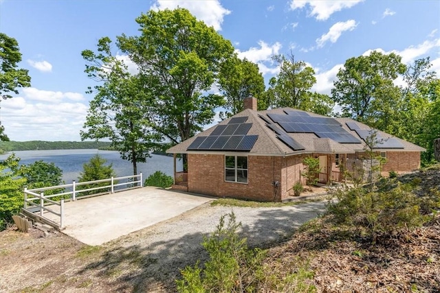 15100 Railroad Cut Rd, Rogers, AR 72756 - view of property exterior with solar panels, a water view, brick siding, and a chimney