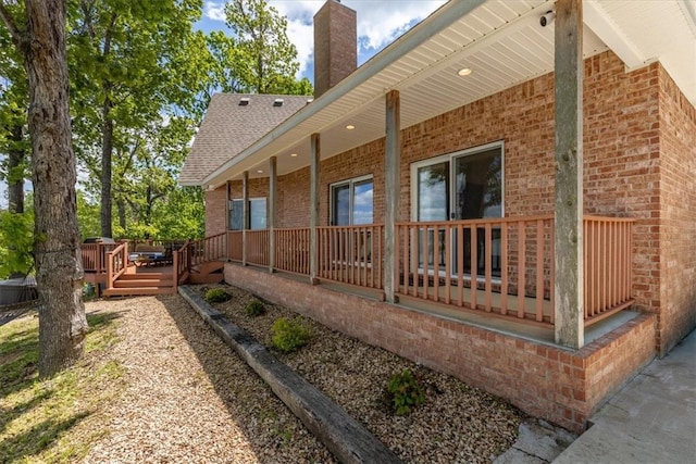 15100 Railroad Cut Rd, Rogers, AR 72756 - view of property exterior with brick siding, a chimney, roof with shingles, and a deck