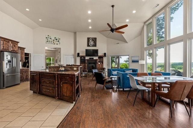 15100 Railroad Cut Rd, Rogers, AR 72756 - kitchen featuring stainless steel fridge, high vaulted ceiling, a ceiling fan, dark brown cabinetry, and a center island