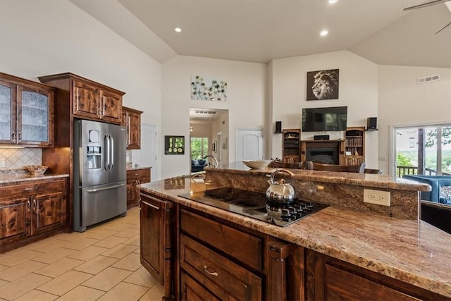 15100 Railroad Cut Rd, Rogers, AR 72756 - kitchen featuring stainless steel fridge, black electric cooktop, high vaulted ceiling, a fireplace, and light stone counters