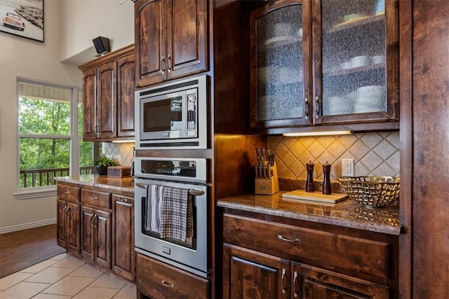 15100 Railroad Cut Rd, Rogers, AR 72756 - kitchen with appliances with stainless steel finishes, tasteful backsplash, dark brown cabinetry, glass insert cabinets, and baseboards