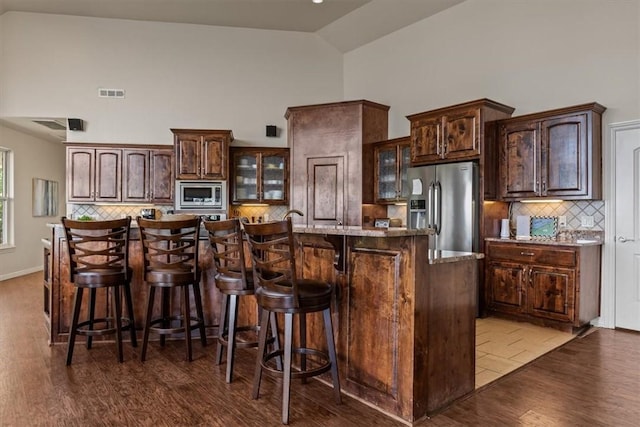 15100 Railroad Cut Rd, Rogers, AR 72756 - kitchen featuring appliances with stainless steel finishes, high vaulted ceiling, dark wood finished floors, backsplash, and glass insert cabinets