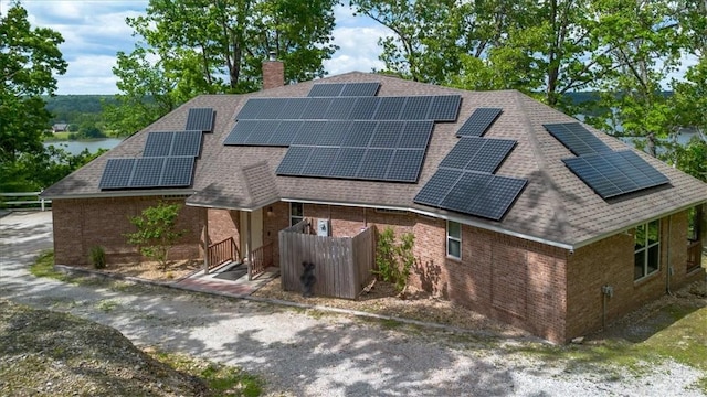 15100 Railroad Cut Rd, Rogers, AR 72756 - view of front of house with roof with shingles, brick siding, a chimney, and roof mounted solar panels