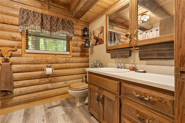 5287 Forgeson Rd, Harrison, AR 72601 - bathroom with wood ceiling with exposed beams, toilet, rustic walls, vanity, and wood finished floors