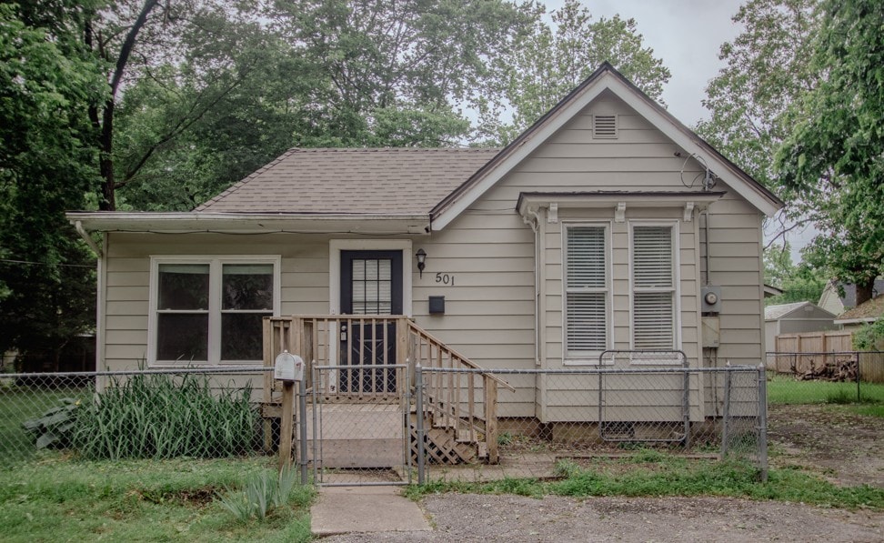 501 W Center Ave, Springdale, AR 72764 - bungalow with a fenced front yard, a shingled roof, and a gate