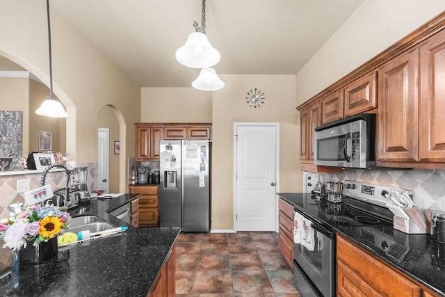 4007 W Song Bird Pl, Fayetteville, AR 72704 - kitchen with stainless steel appliances, arched walkways, brown cabinetry, tasteful backsplash, and hanging light fixtures