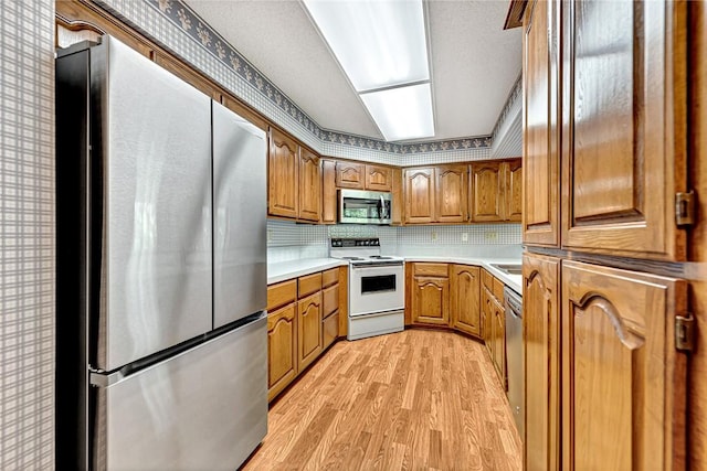 22 Marina Cir, Bella Vista, AR 72715 - kitchen featuring stainless steel appliances, light wood-style flooring, light countertops, brown cabinets, and decorative backsplash