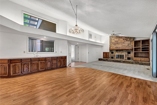 22 Marina Cir, Bella Vista, AR 72715 - unfurnished living room featuring a textured ceiling, a ceiling fan, a fireplace, light wood finished floors, and high vaulted ceiling