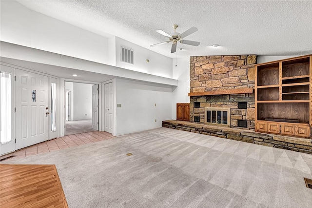 22 Marina Cir, Bella Vista, AR 72715 - unfurnished living room with carpet flooring, a textured ceiling, ceiling fan, a stone fireplace, and tile patterned floors