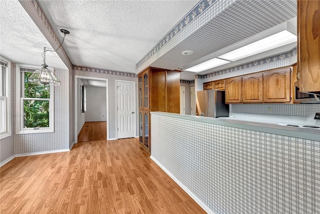 22 Marina Cir, Bella Vista, AR 72715 - kitchen with a textured ceiling, light wood-type flooring, brown cabinetry, wallpapered walls, and baseboards