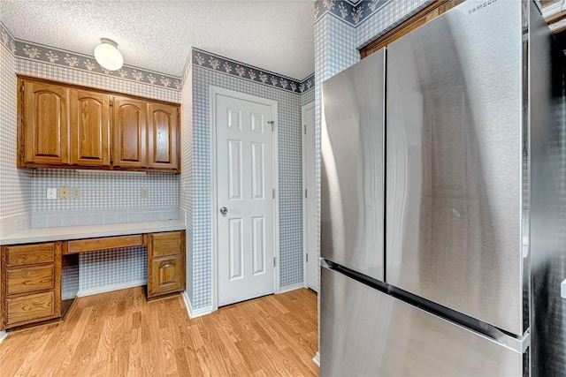 22 Marina Cir, Bella Vista, AR 72715 - kitchen featuring freestanding refrigerator, wallpapered walls, light wood-type flooring, light countertops, and brown cabinets