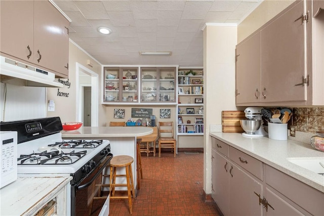 1600 Westwood Ave, Springdale, AR 72762 - kitchen with range with gas stovetop, light countertops, under cabinet range hood, ornamental molding, and glass insert cabinets