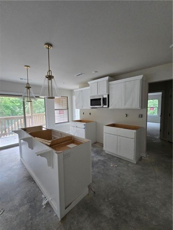 3 Drem Cir, Bella Vista, AR 72715 - kitchen featuring stainless steel microwave, plenty of natural light, concrete flooring, and white cabinets
