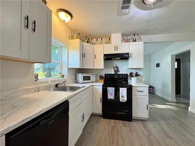 1105 Gibson St, Ozark, AR 72949 - kitchen with black appliances, under cabinet range hood, a sink, light wood-style floors, and white cabinets