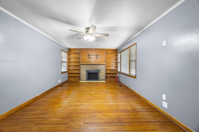 713 Young St, Springdale, AR 72764 - unfurnished living room featuring ornamental molding, a ceiling fan, a fireplace, hardwood / wood-style flooring, and plenty of natural light