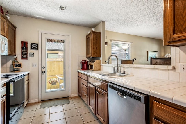 14 Jordan Ln, Bentonville, AR 72712 - kitchen with black electric range, stainless steel dishwasher, a sink, decorative backsplash, and white microwave