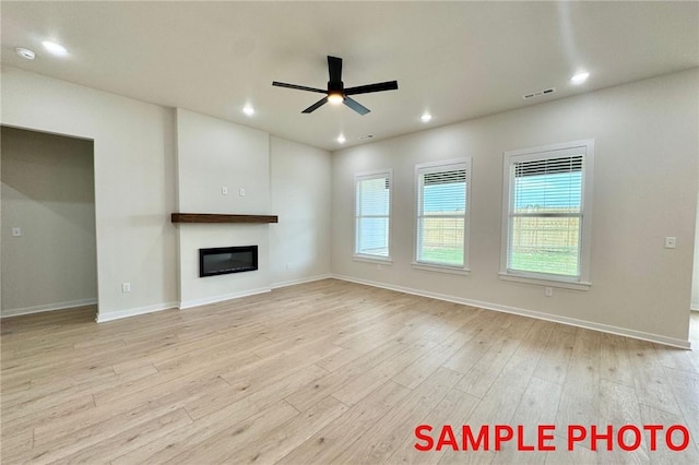 5902 SW Desert Ave, Bentonville, AR 72713 - unfurnished living room with ceiling fan, light wood finished floors, a glass covered fireplace, baseboards, and recessed lighting