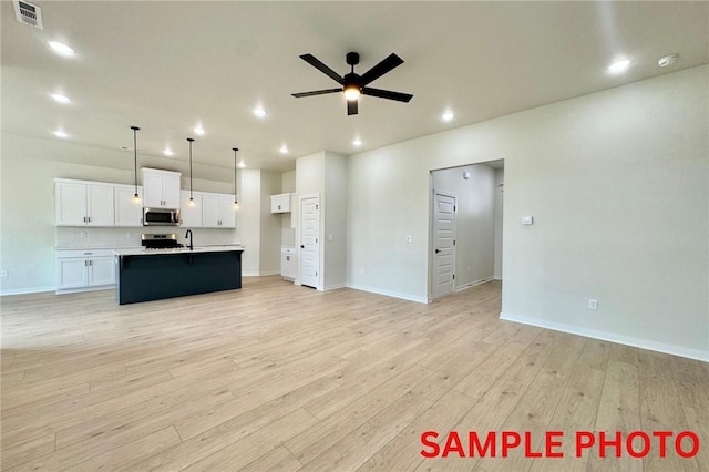 5902 SW Desert Ave, Bentonville, AR 72713 - unfurnished living room with a ceiling fan, light wood-type flooring, recessed lighting, baseboards, and a sink
