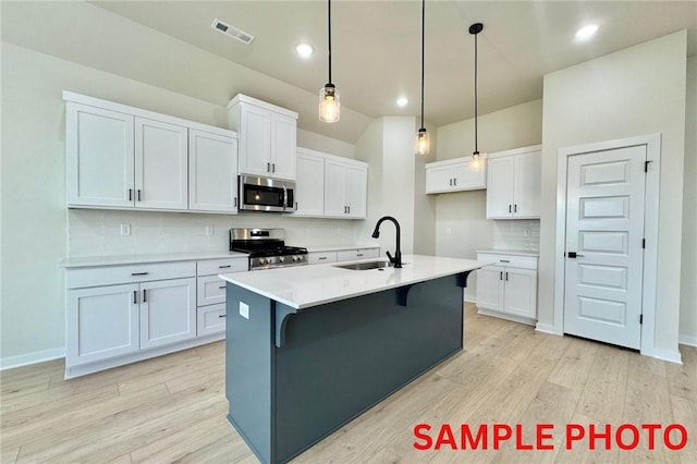 5902 SW Desert Ave, Bentonville, AR 72713 - kitchen with appliances with stainless steel finishes, a sink, light wood finished floors, tasteful backsplash, and white cabinets