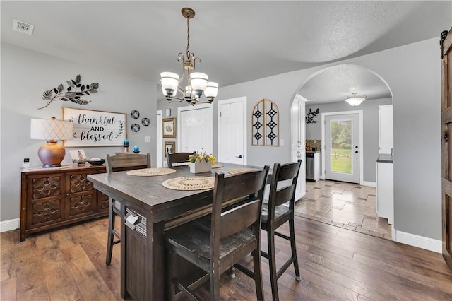 1630 S Dixieland Rd, Rogers, AR 72758 - dining room featuring arched walkways, a chandelier, wood-type flooring, and baseboards