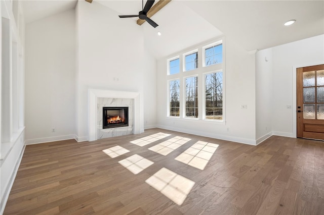 10 Rushden Ln, Bella Vista, AR 72714 - unfurnished living room with high vaulted ceiling, a high end fireplace, a ceiling fan, wood finished floors, and baseboards