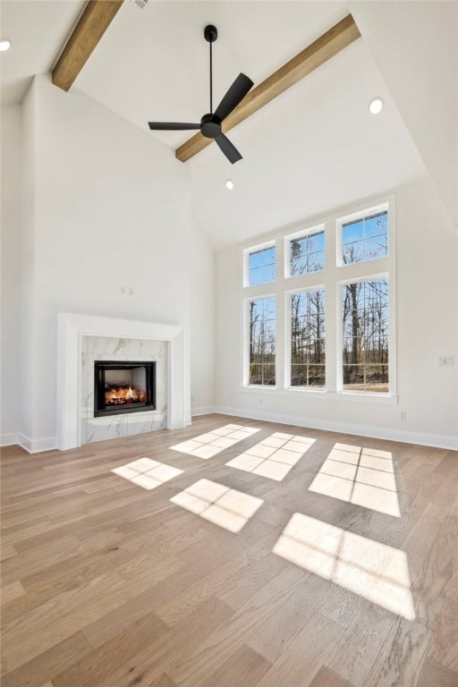 10 Rushden Ln, Bella Vista, AR 72714 - unfurnished living room with beamed ceiling, a high end fireplace, wood finished floors, a ceiling fan, and high vaulted ceiling