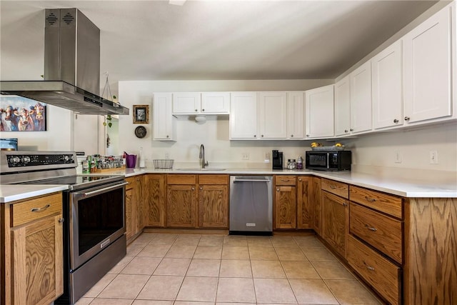 909 11th St, Bentonville, AR 72712 - kitchen with stainless steel appliances, a sink, island exhaust hood, white cabinetry, and light countertops