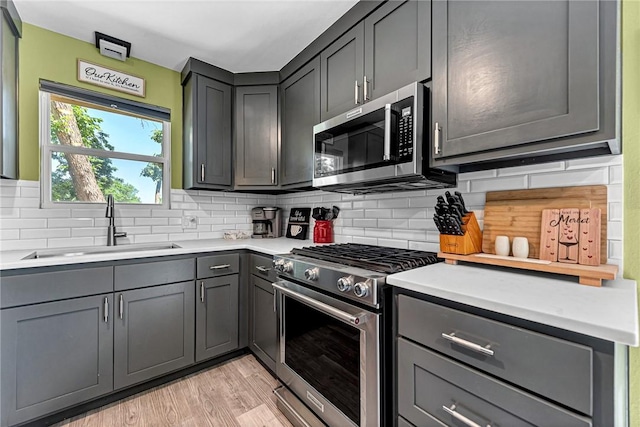312 NW J St, Bentonville, AR 72712 - kitchen featuring appliances with stainless steel finishes, a sink, decorative backsplash, and light countertops