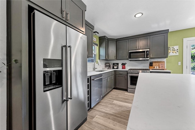 312 NW J St, Bentonville, AR 72712 - kitchen featuring stainless steel appliances, a sink, light countertops, tasteful backsplash, and light wood finished floors