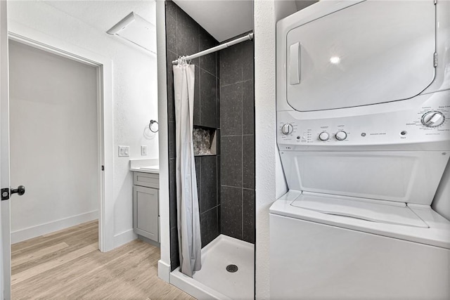 312 NW J St, Bentonville, AR 72712 - full bathroom featuring stacked washer / drying machine, a stall shower, wood finished floors, vanity, and baseboards