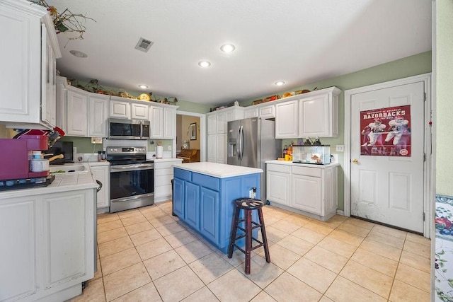 2977 Quartz Dr, Fayetteville, AR 72704 - kitchen with appliances with stainless steel finishes, light countertops, white cabinetry, blue cabinetry, and recessed lighting