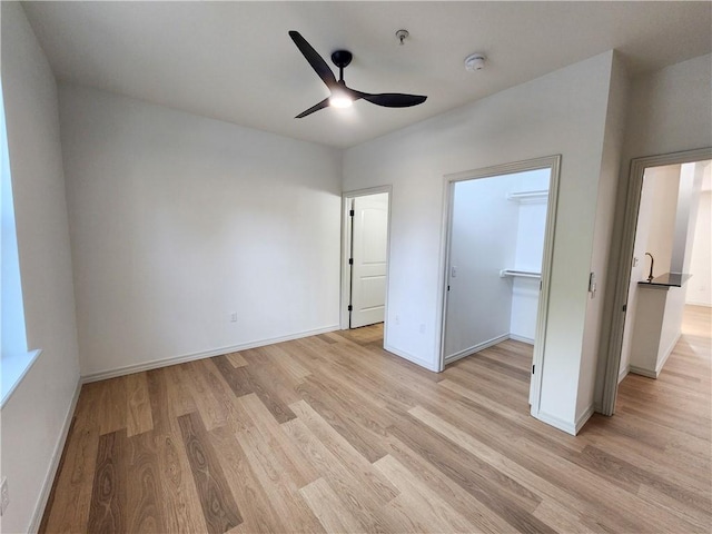 1115 N Leverett Ave Unit 102, Fayetteville, AR 72703 - unfurnished bedroom with light wood-type flooring, baseboards, a spacious closet, ceiling fan, and a closet