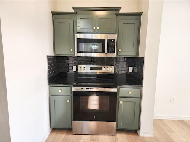 1115 N Leverett Ave Unit 102, Fayetteville, AR 72703 - kitchen featuring appliances with stainless steel finishes, green cabinetry, dark countertops, and light wood-type flooring