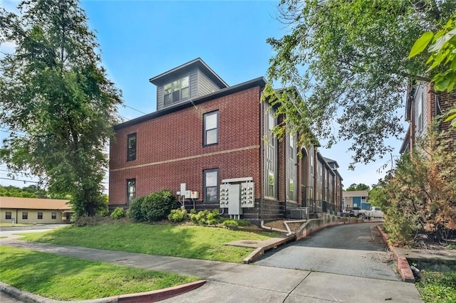 1115 N Leverett Ave Unit 102, Fayetteville, AR 72703 - view of side of home featuring brick siding, a lawn, and central AC